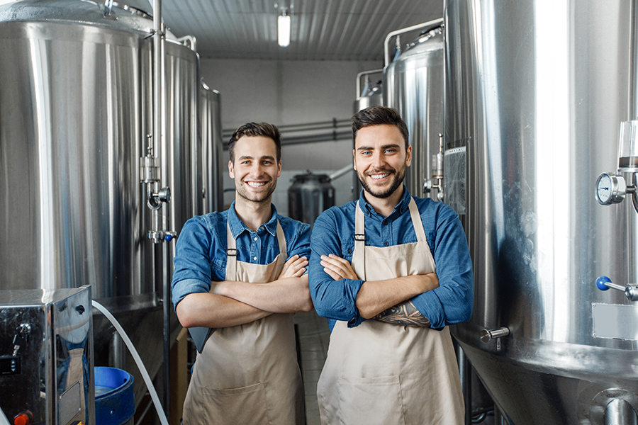 business owners in front of new business equipment for brewing