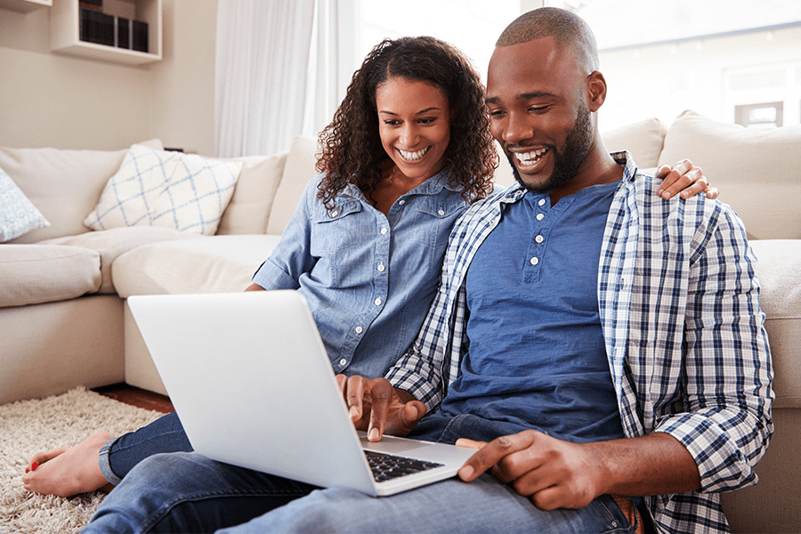 couple sitting on couch looking at finances on a computer