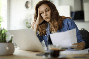 woman reviewing bank statement and frustrated by checking account fees for her small business