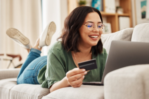 young woman shopping online with her debit card from her couch