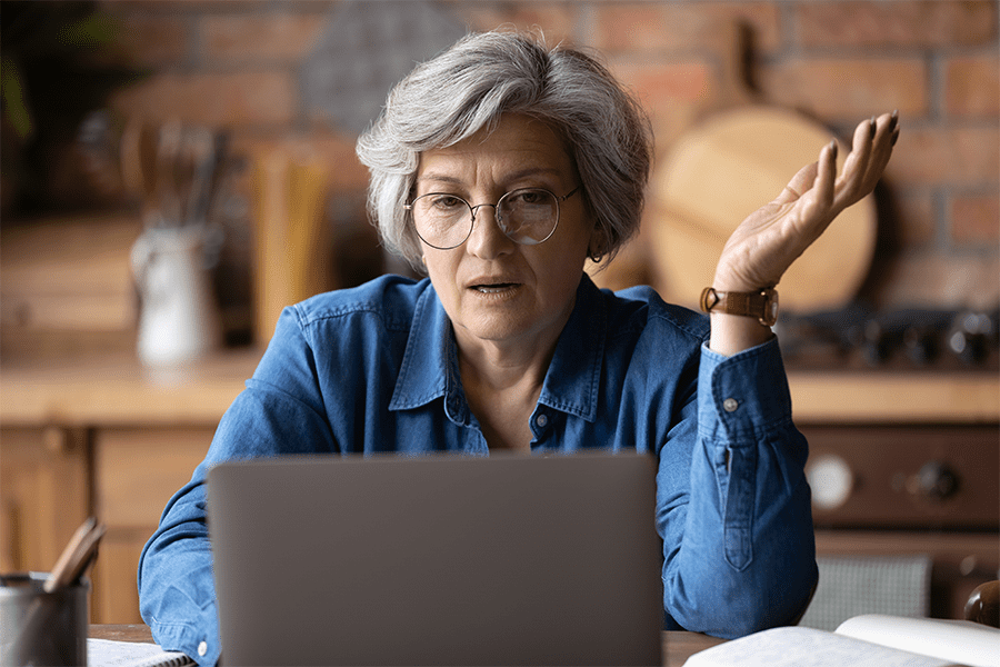upset elderly woman looking at her computer
