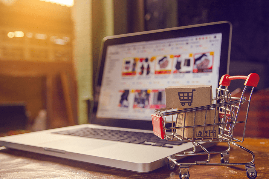 shopping cart in front of a computer shopping online